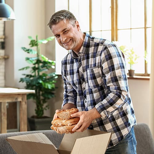 man packing kitchen moving supplies with packing paper roll