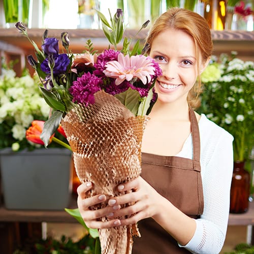 florist holding a bouquet wrapped with honeycomb packing paper